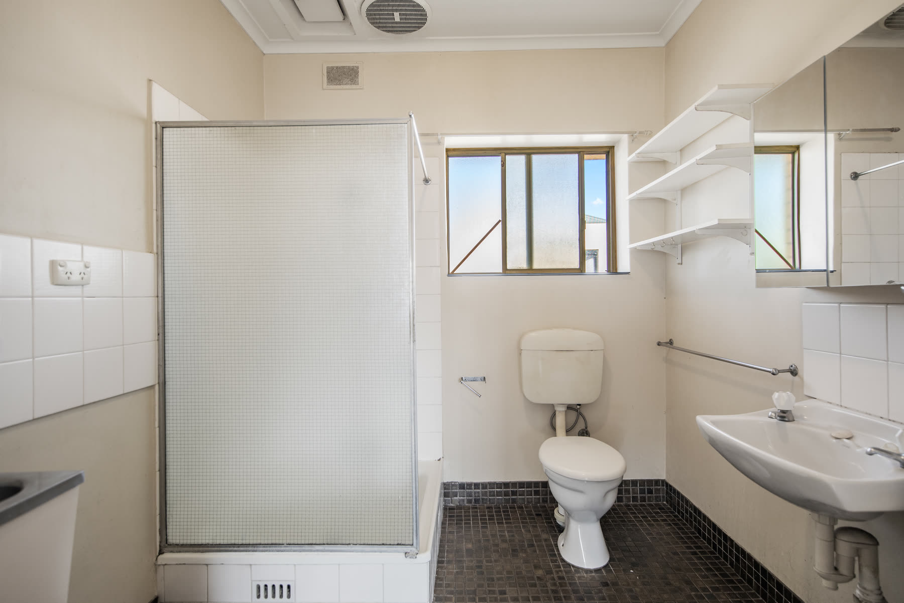 Original bathroom with dark mosaic floor tiles before renovation